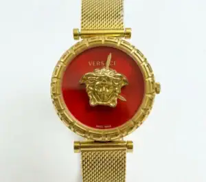 Gold Medusa watch with red dial and mesh strap, luxury fashion accessory.