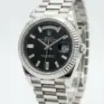 Rolex Day-Date watch with black dial, baguette hour markers, and stainless steel bracelet.